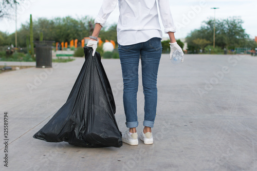 Person holding a trash bad and a plastic bottle