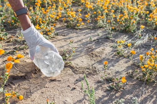 Hand in white gloves taking a plastic bottle from the floor