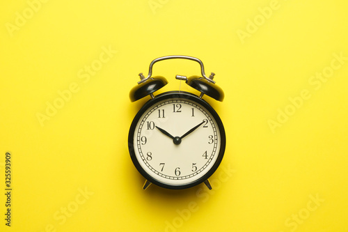 twin bell alarm clock on yellow background. copy space. flat lay