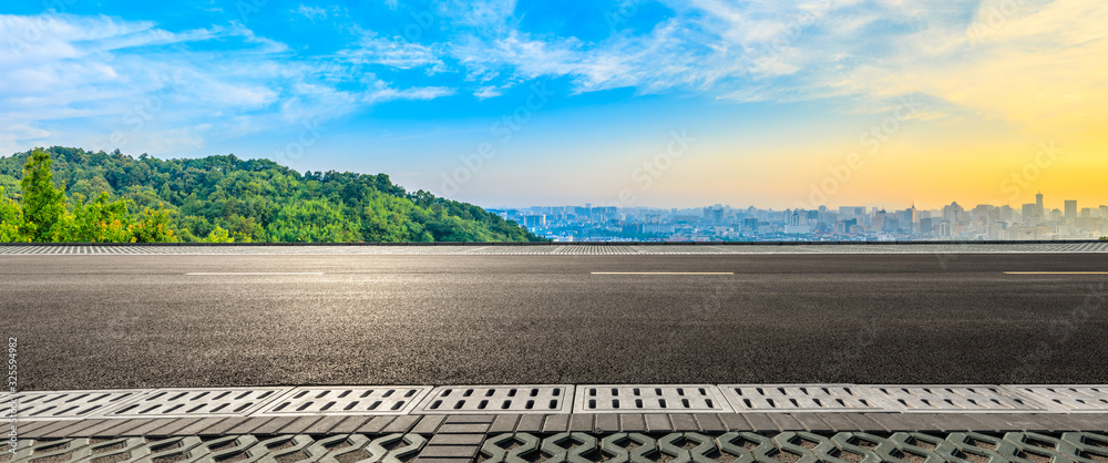 Empty asphalt road and city skyline with green mountain at sunrise in Hangzhou,China. Empty asphalt road and city skyline with green mountain at sunrise in Hangzhou,China.
