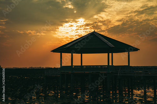 Vintage Wooden Pavilion is under construction with light from sunset or evening time at water lake of public park of Bueng See Fai, Phichit Province, Thailand. photo