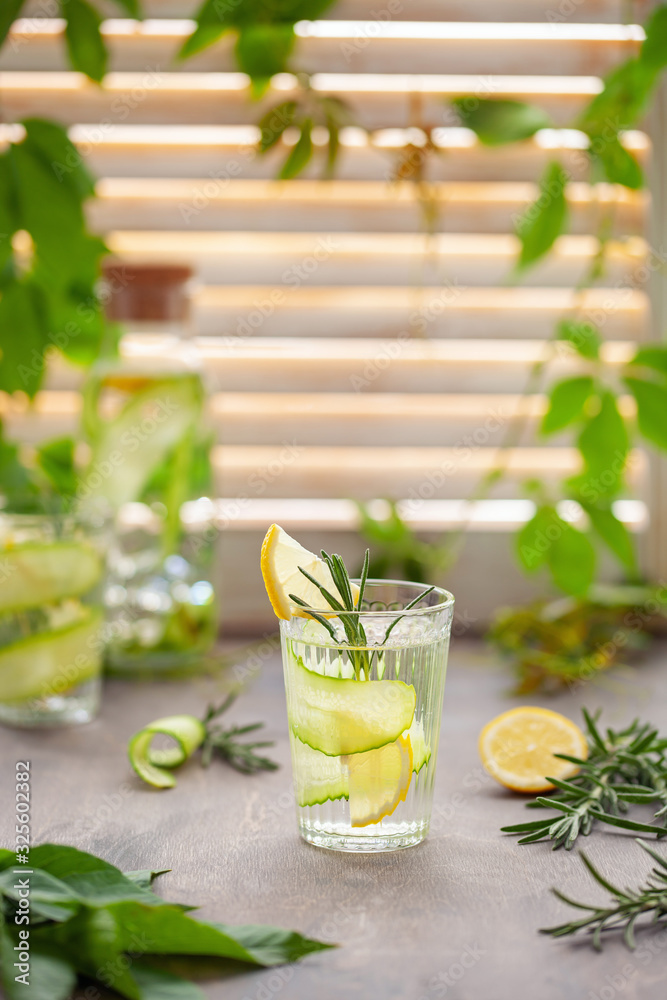 Refreshing water with lemon, cucumber and rosemary in a glass on the table.
