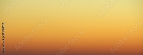 Flaming sky over the horizon during sunset or sunrise. Bright iridescent colors of yellow, orange and red. Colored background for text and design