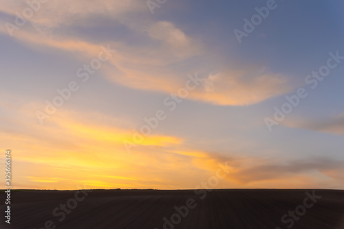 Scenic countryside sunset landscape with a plain wild grass field horizon view and a beauty rosy clouds background