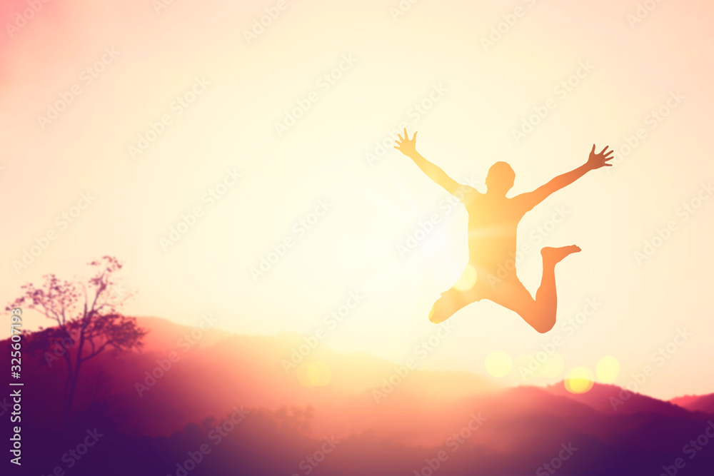 Happy man jumping at top of mountain with sunset sky abstract background.