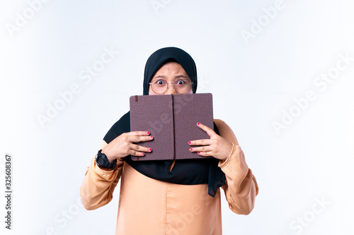 Student female with bugged eyes covering his mouth with opened book, realizing that he is late for exam. On white background