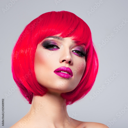 Beautiful young fashion woman with pink lipstick. Glamour fashion model with bright make-up, at studio. Beauty portrait. Caucasian Model with bob hairstyle colored in pink. Eyes with vivid makeup.