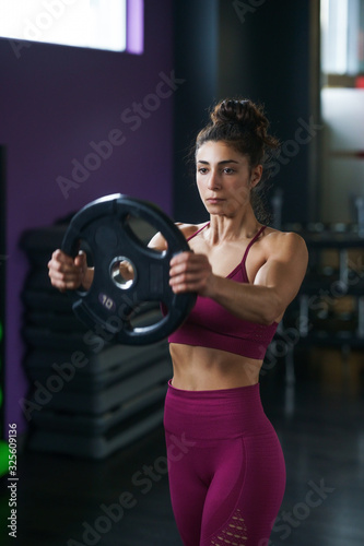 Athletic woman doing triceps push-ups with a barbell plate