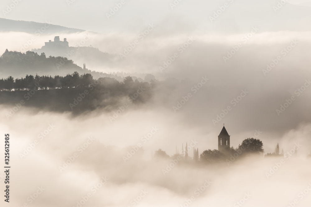 Surreal view of of a little town in Umbria (Italy) almost completely hidden by fog