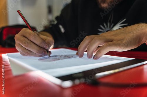 фотографія tattoo artist tracing a design on a light table