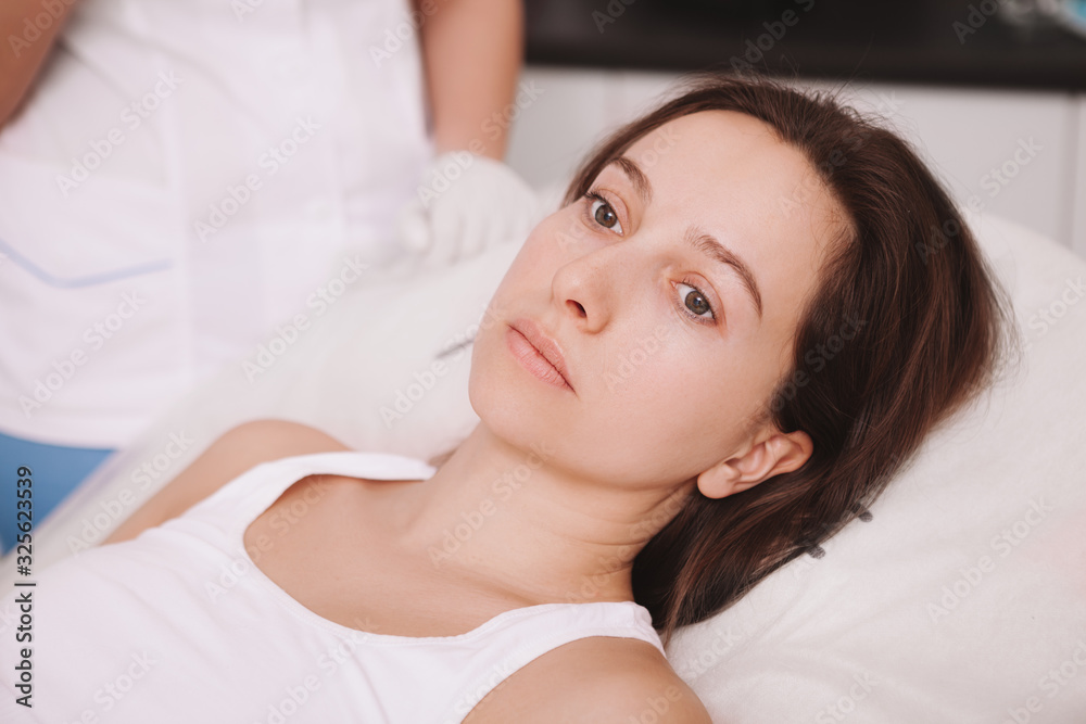 Close up of a sad female patient at the hospital. Unhappy young woman lying in her bed at the clinic, waiting for surgery