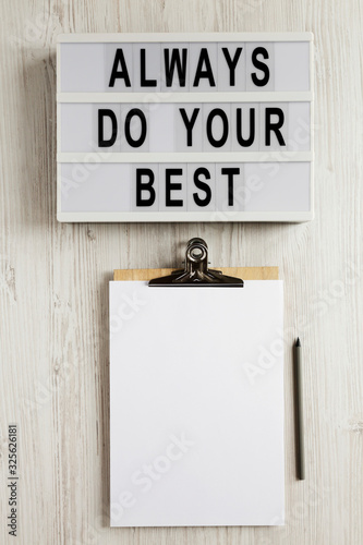 'Always do your best' words on a modern board, clipboard with blank sheet of paper on a white wooden background, top view. Overhead, from above, flat lay. photo