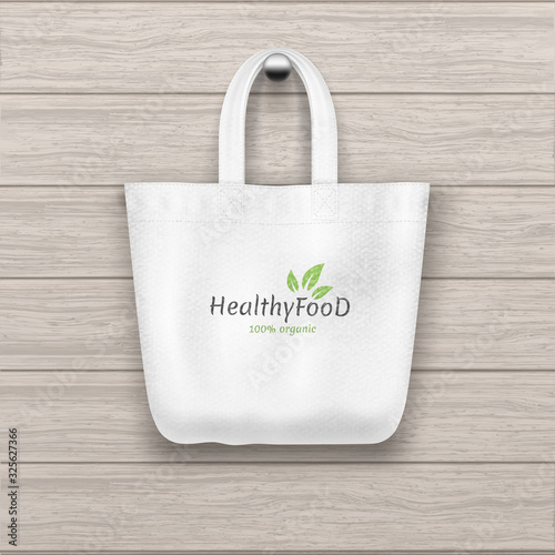 Textile textured white tote with logo bag hanging on the wooden plank textured wall.