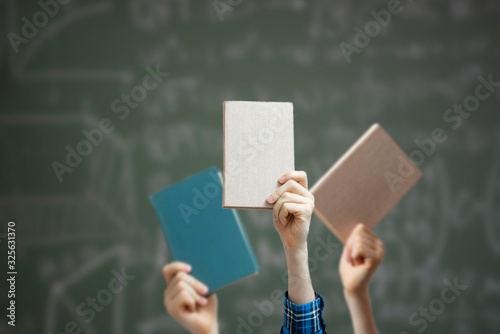 group of raised people hands holding books isolated against the colorful background, share knowledge and study