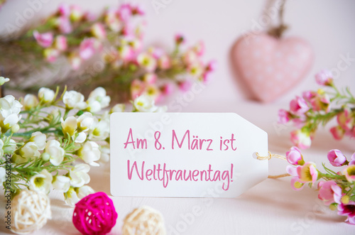 Label With German Text Weltfrauentag Means International Womens Day. Rose And White Flowers With Heart Decoration. photo