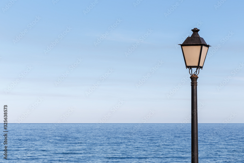 Streetlamp off on a sunny day and the calm sea in the background