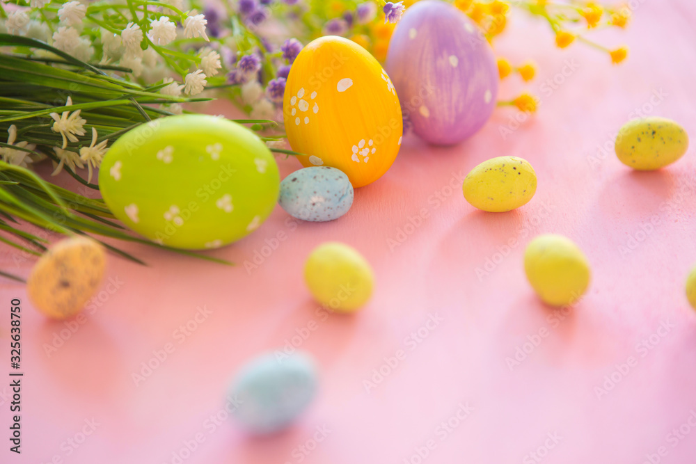Easter eggs and blooming branches of flowers on pink wooden background.