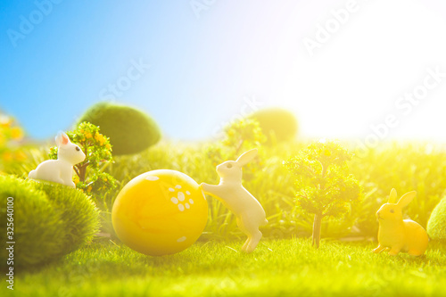 Easter eggs with easter bunny toys on green grass meadow on sunset. photo