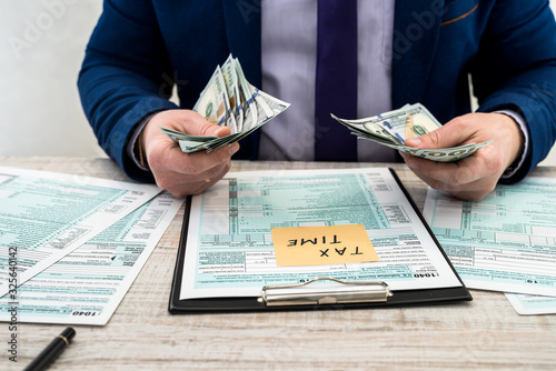 Wallpaper Mural businessman counts dollars and fills out a US 1040 individual tax form. Sticker with the inscription tax time Torontodigital.ca