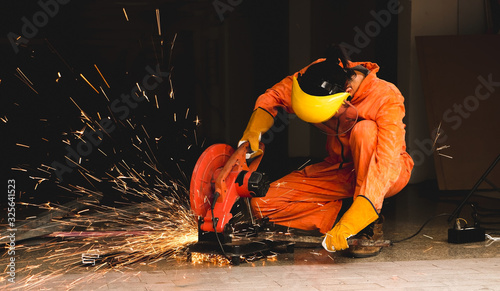 Photos Worker  in orange  jumpsuit using electric wheel grinding on steel