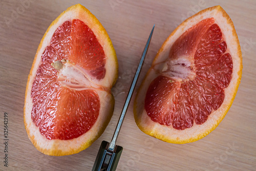 a penknife cut a grapefruit on a wooden background