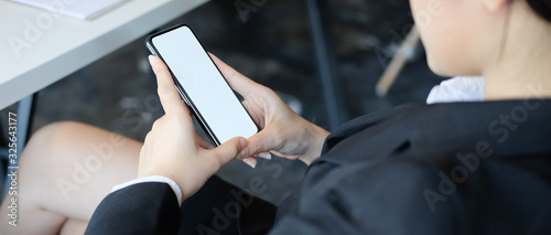 Cropped shot view of woman hands holding smart phone with blank copy space screen for your text message or information content  female reading text message on cell telephone during in urban setting.