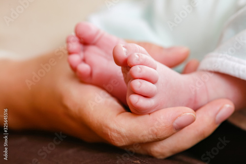 Main d'une mère tenant les petits pieds de son bébé © AlexQ