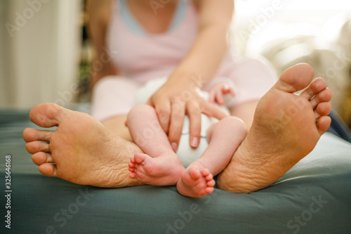 Pieds de bébé entre les pieds de sa mère