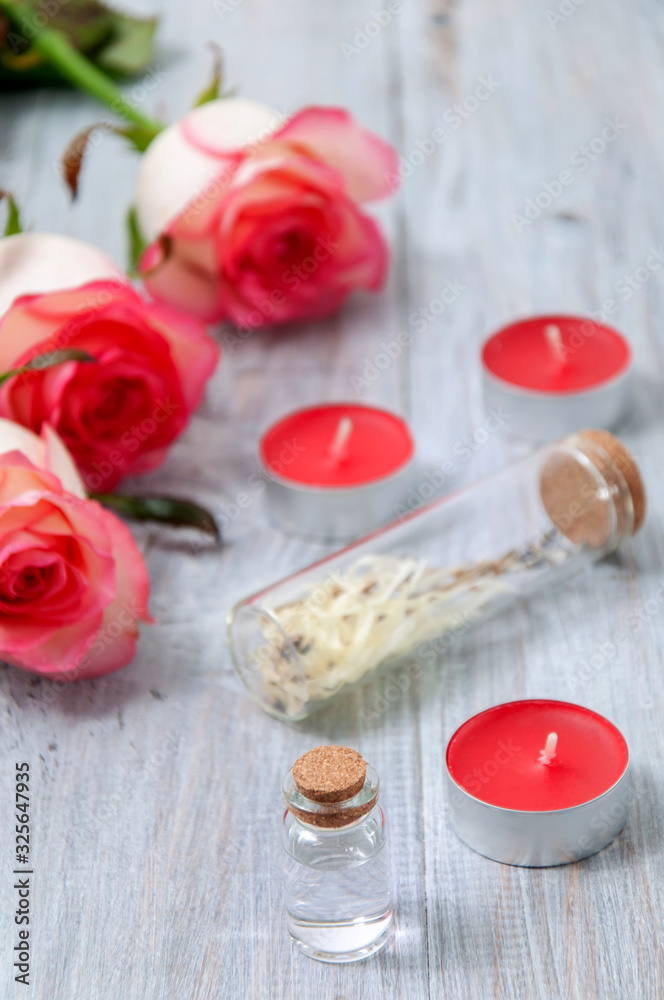Pink roses, oil bottles and candles on a gray wooden table. March 8. Valentine's Day. Greeting card. Romantic and beautiful background. Spa treatments. Personal care. Love and beauty. Pink roses, oil bottles and candles on a gray wooden table. March 8. Valentine's Day. Greeting card. Romantic and beautiful background. Spa treatments. Personal care. Love and beauty.