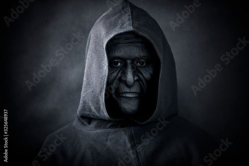Scary figure in hooded cloak with mask