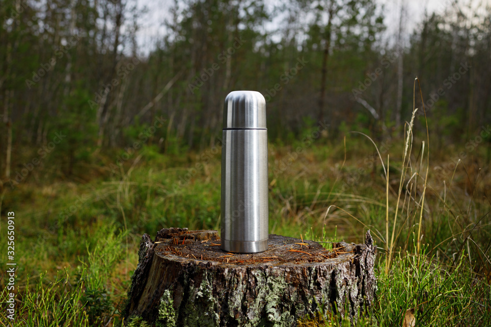 Steel thermos on an old stump in the forest