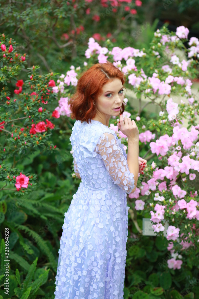 beautiful red-haired girl in arranger where azalea blooms in a colorful flying dress beautiful red-haired girl in arranger where azalea blooms in a colorful flying dress