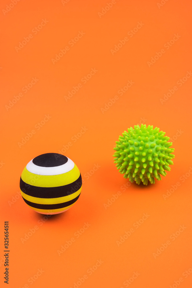 Set of two green myofascial release and massage balls for trigger points over burnt orange color background. Self body care massage and stress, pain relief concept. Set of two green myofascial release and massage balls for trigger points over burnt orange color background. Self body care massage and stress, pain relief concept.