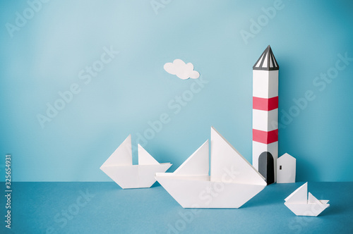 Paper boat, lighthouse on blue background.
