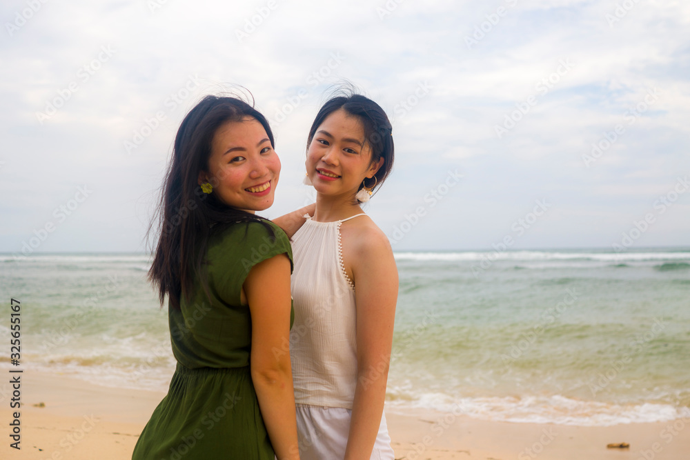 young beautiful and happy couple of attractive Asian Korean women walking together relaxed at the beach enjoying holidays having fun feeling free and joyful