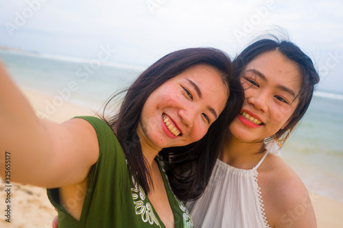young beautiful and happy couple of attractive Asian Korean women at the beach enjoying holidays having fun taking selfie together with mobile phone in girls friendship © TheVisualsYouNeed