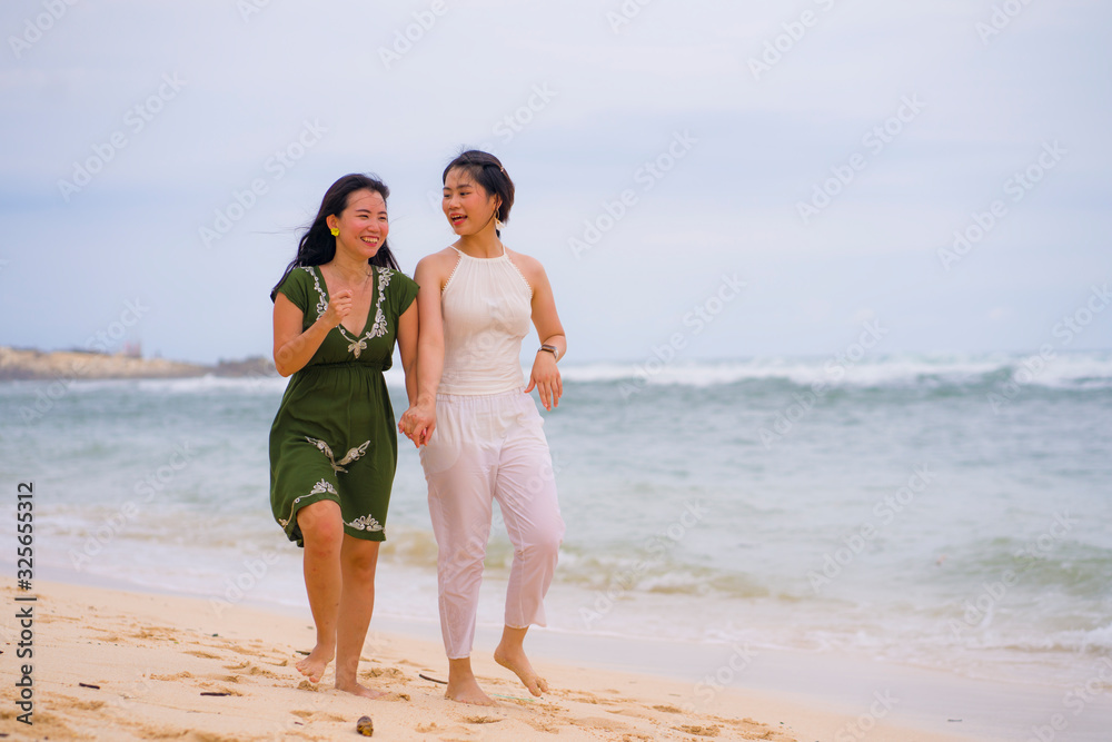 young beautiful and happy couple of attractive Asian Korean women walking together relaxed at the beach enjoying holidays having fun feeling free and joyful young beautiful and happy couple of attractive Asian Korean women walking together relaxed at the beach enjoying holidays having fun feeling free and joyful
