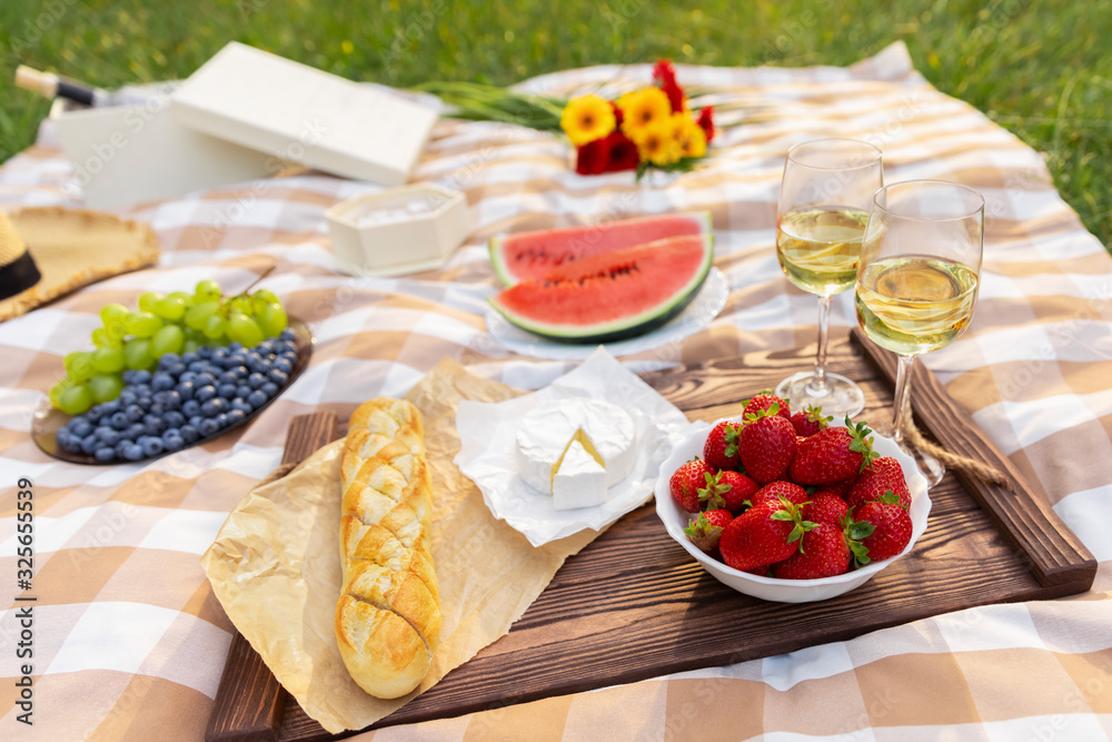 Romantic picnic in nature. The beauty of the setting sun, fresh fruits and wine.