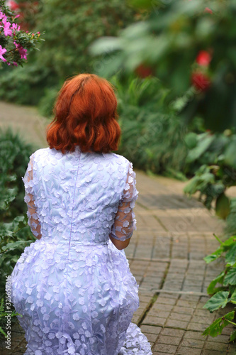 beautiful red-haired girl in arranger where azalea blooms in a colorful flying dress photo