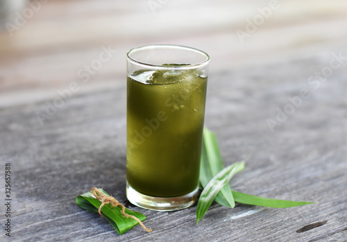 Pandan (Pandanus amaryllifolius) ice cool tea with green leaves on wooden table, herbal soft drink