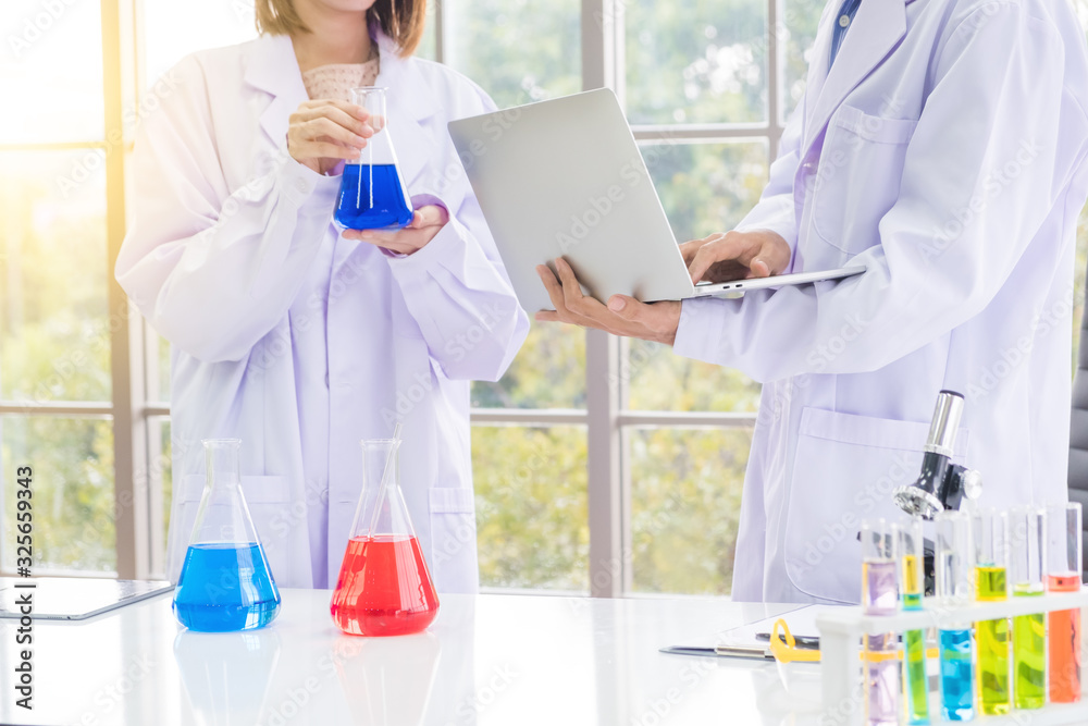 Two scientists are researching research using notebooks or laptop for research. At the Chemistry Laboratory. Two scientists are researching research using notebooks or laptop for research. At the Chemistry Laboratory.
