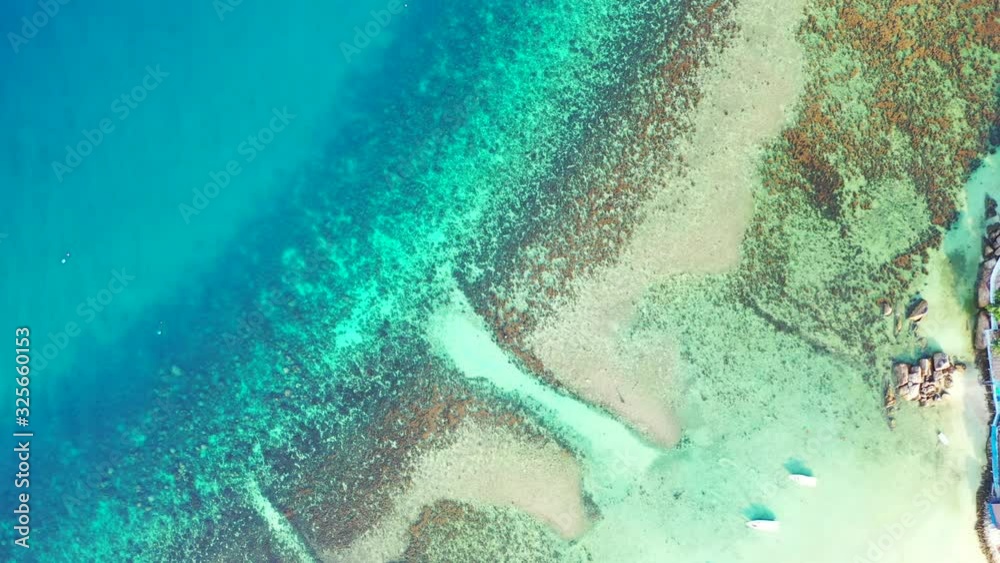 human-made cuts in the coral reef serve as a passage for the boats to access tropical beach. Vertical tropical sea background