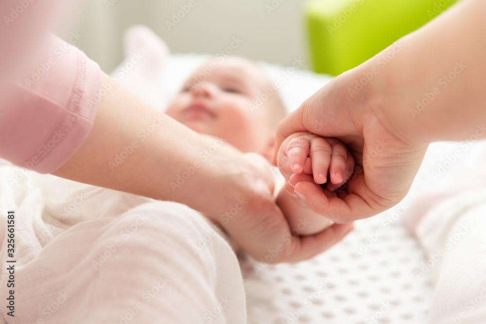 Mother gently massaging her baby boy while applying body lotion to his skin. Baby massage background. Hands close up. Mother gently massaging her baby boy while applying body lotion to his skin. Baby massage background. Hands close up.