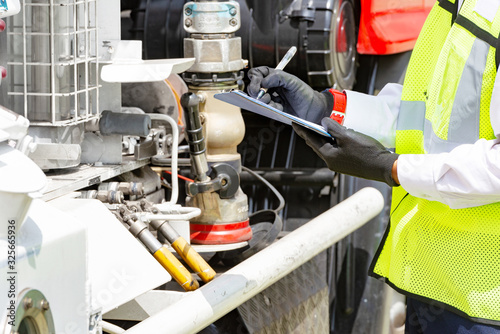 An officer with clipboard checking truck engine