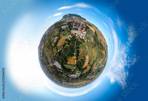 Little planet view of fortress on top of the mountain, fortifications, in the background mountains and the city. The concept of tourism and holidays in Europe. San Marino, Italy