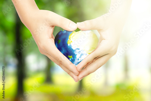 Human hands holding the earth with heart shape in the park