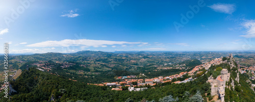 Aerial wide view on medieval fortress on top of the mountain, fortifications, in the background mountains and the city. The concept of the best places for tourism in Europe. San Marino, Italy