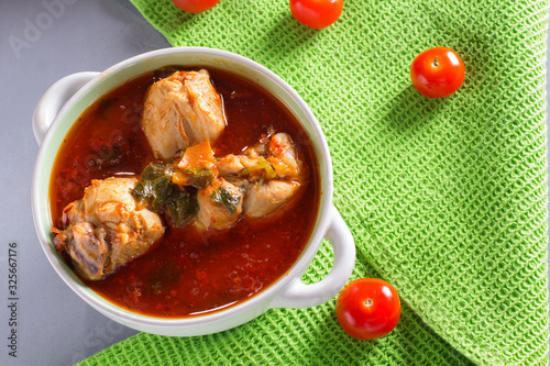 Chakhokhbili with chicken legs, parsley and tomatoes on a gray background. Chicken in tomato sauce. photo