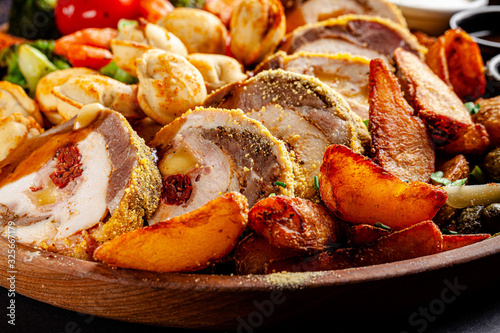 Turkish cuisine. A large wooden board with assorted different meats, beef, lamb, chicken rolls, fried dumplings, grilled vegetables and potatoes. background image, copy space text