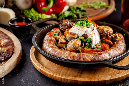 Turkish oriental cuisine. Homemade sausage, with fried mushrooms, green onions, and kaimak sauce. Serving dishes in restaurant in a cast-iron pan. background image, copy space text